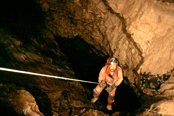Caver rappelling into vertical shaft inside Rat's Nest Cave, Canmore Alberta — rope descent during exploration of Canadian Rockies cave system near Banff